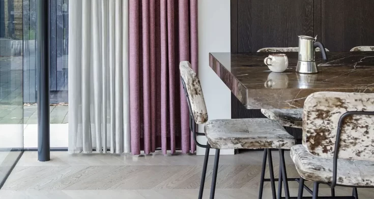 Stijlvolle eetkamer met een marmeren eettafel, fluwelen eetkamerstoelen en een combinatie van transparante en bordeauxrode gordijnen voor een moderne en warme uitstraling.