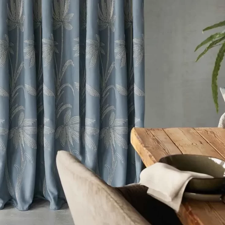 Blauwe gordijnen met subtiel bladpatroon in een eetkamer met natuurlijke elementen