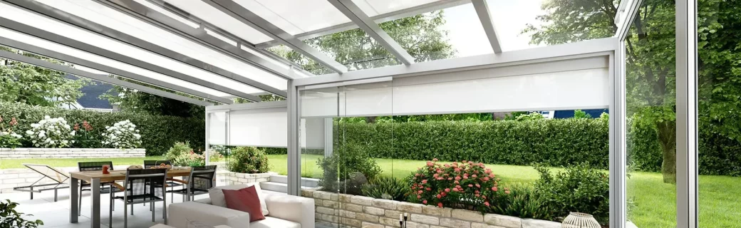 Moderne serre met glazen wanden, uitschuifbare zonwering en groen uitzicht