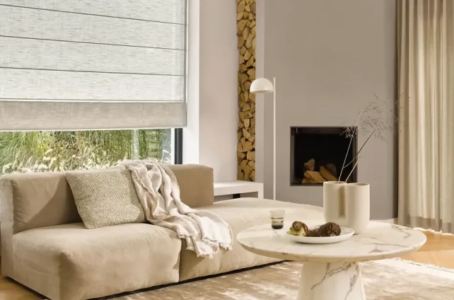 Stijlvolle woonkamer met grote ramen voorzien van beige vouwgordijnen, die zorgen voor een zachte lichtinval en een warme uitstraling.