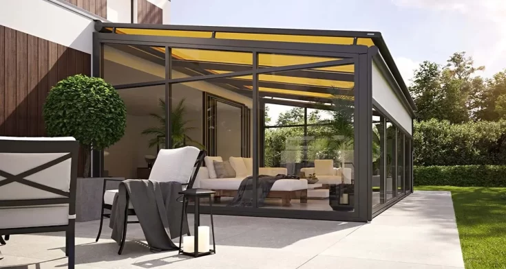 Een grote, moderne serre met daarin loungebanken en stoelen en een gele zonwering.