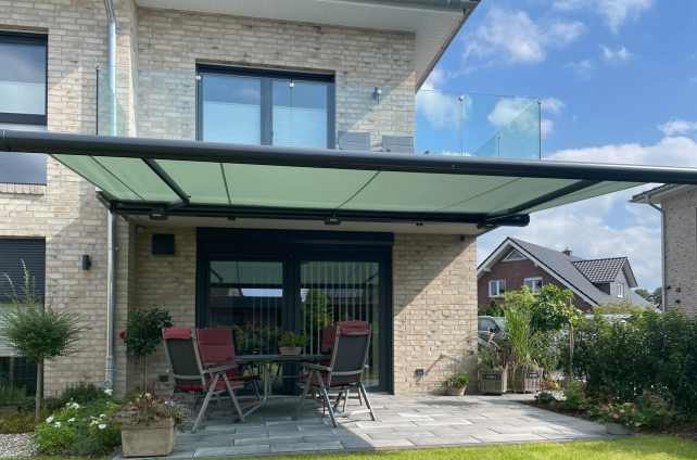 Groen knikarmscherm boven een terras.