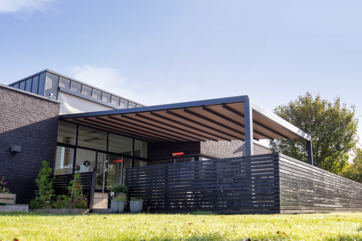 Moderne pergola met zonwering. Een strakke, vrijstaande pergola met uitschuifbare zonwering, perfect geïntegreerd in een moderne woning met een stijlvolle buitenruimte.