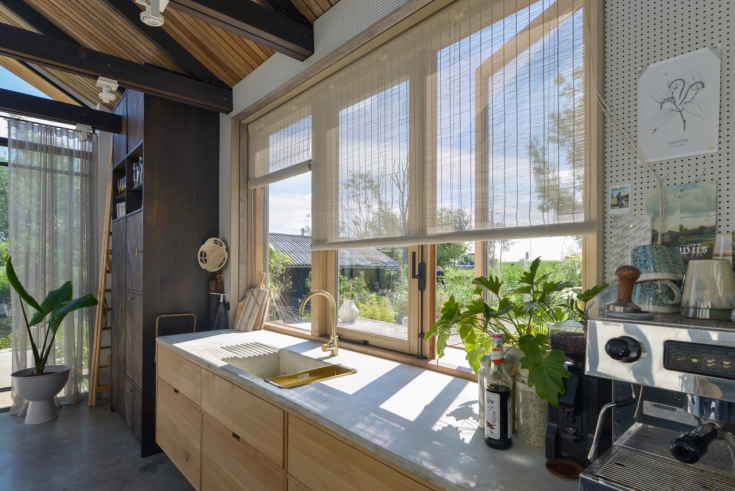 Lichte keuken met houten accenten, voorzien van luchtige, lichtdoorlatende Multisol-rolgordijnen die het buitenlicht sfeervol filteren.