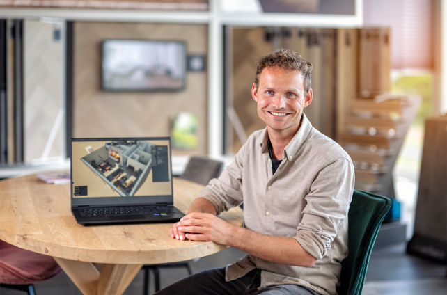 Interieuradviseur van Deventer Zonwering toont 3D-ontwerp op laptop aan ronde houten tafel in showroom