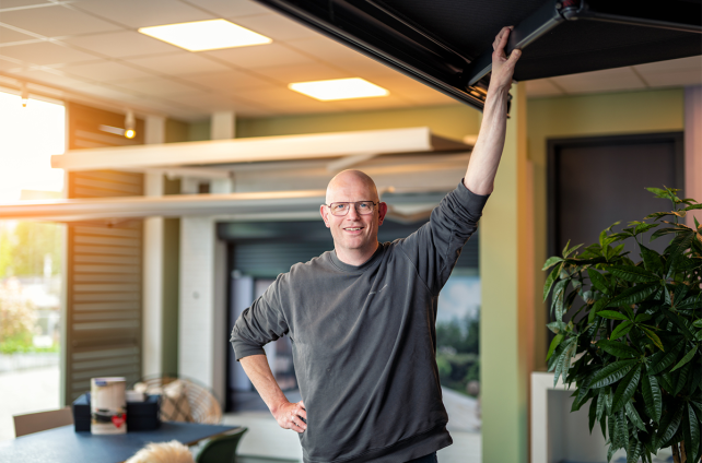 Adviseur van Deventer Zonwering staat onder een knikarmscherm in de showroom