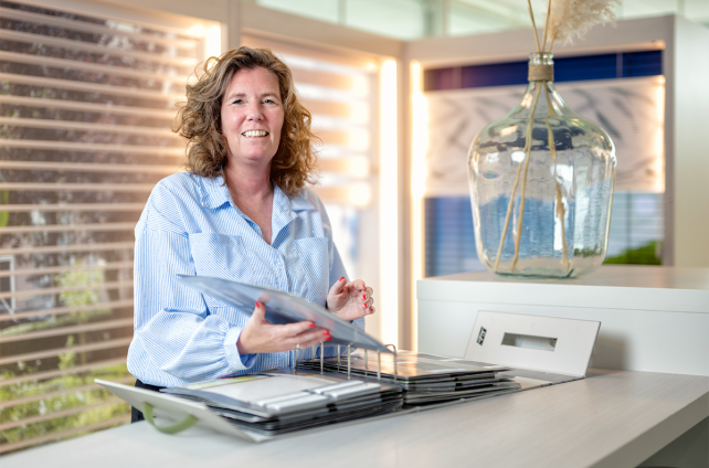 Interieuradviseur van Deventer Zonwering toont stalenboek met jaloezieën in de showroom