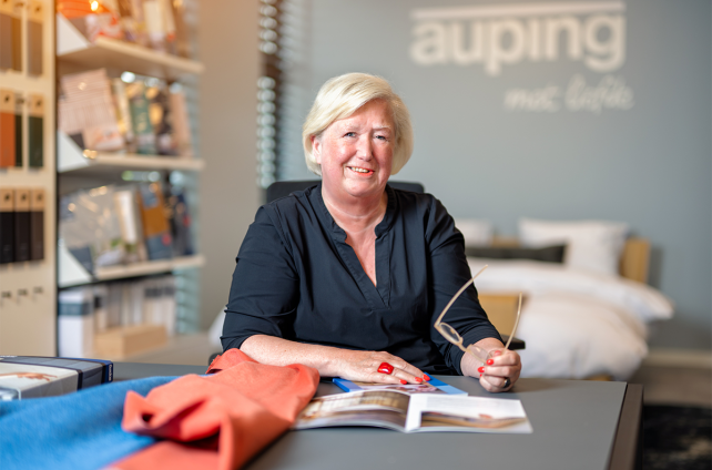 Adviseur van Deventer Zonwering geeft interieuradvies in Auping-studio met brochure en stoffen