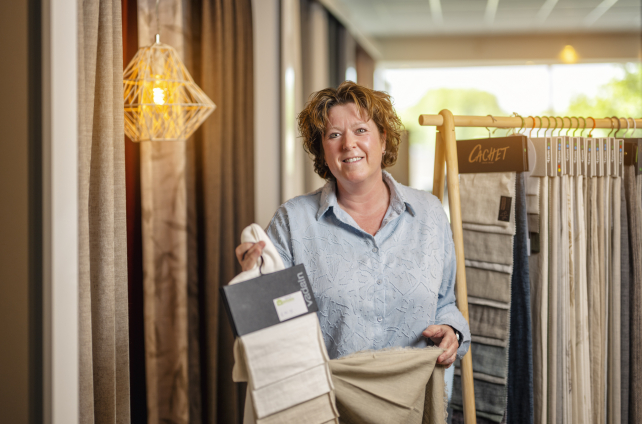 Medewerkster toont verschillende gordijnstoffen aan klant in showroom